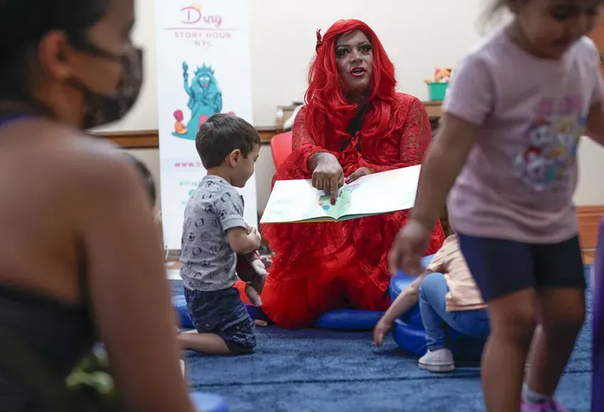 Flame, a drag queen, reads children a story at a public library in New York – Photo by Seth Wenig / AP