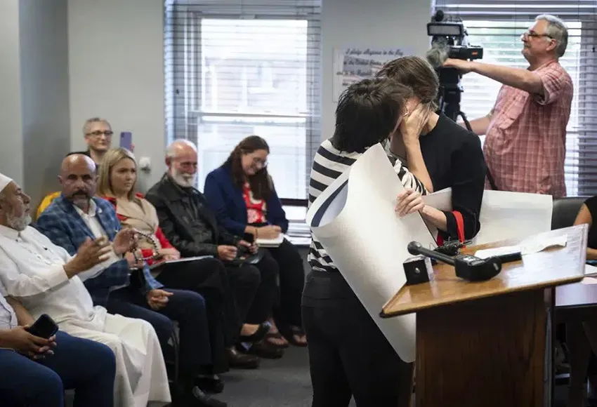 A woman kisses her partner during public comment in Hamtranck City Hall – Photo by Sarahbeth Maney,/ Detroit Free Press via AP