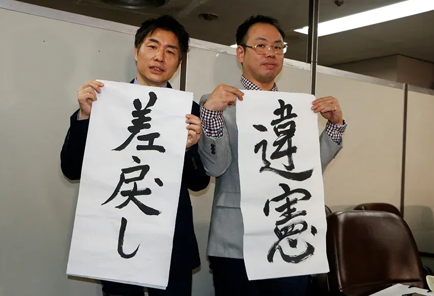 The Plaintiff's lawyers, Kazuyuki Minami and Masafumi Yoshida, hold banners that read "returned" and "unconstitutional" - two main points of the Supreme Court's decision – Photo by Francis Tang / Reuters